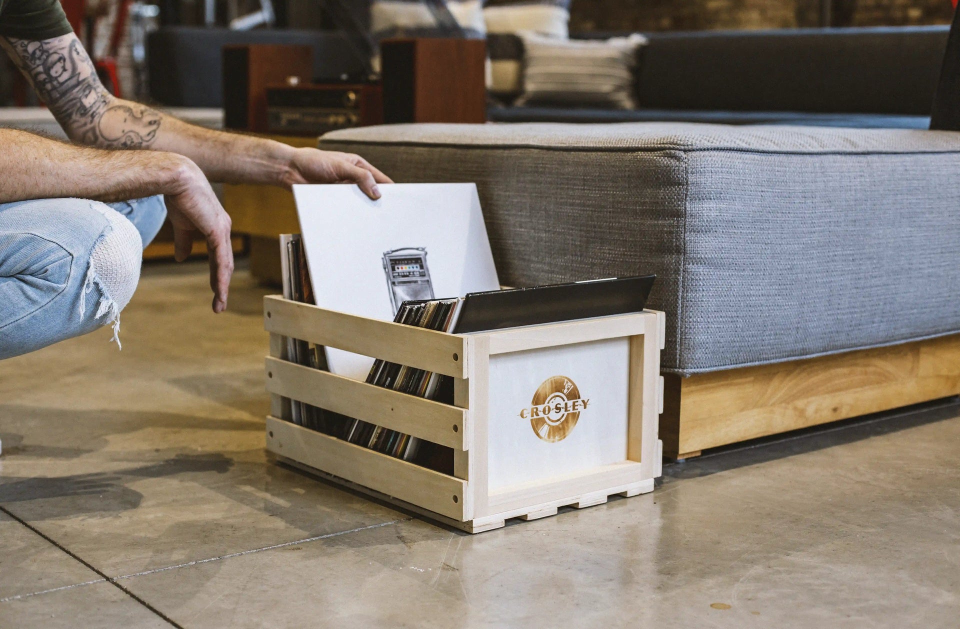 Crosley natural wood vinyl record storage crate displayed in a lifestyle setting with records stored inside