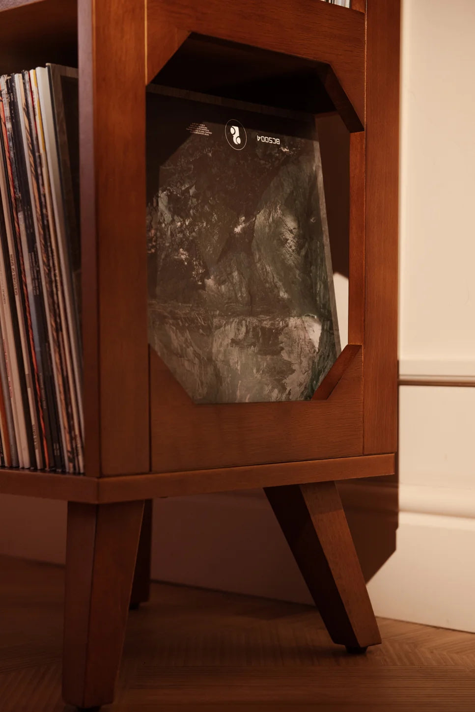 Crosley Asheville Small Vinyl Record Storage Stand in walnut finish displayed in a home entertainment setting